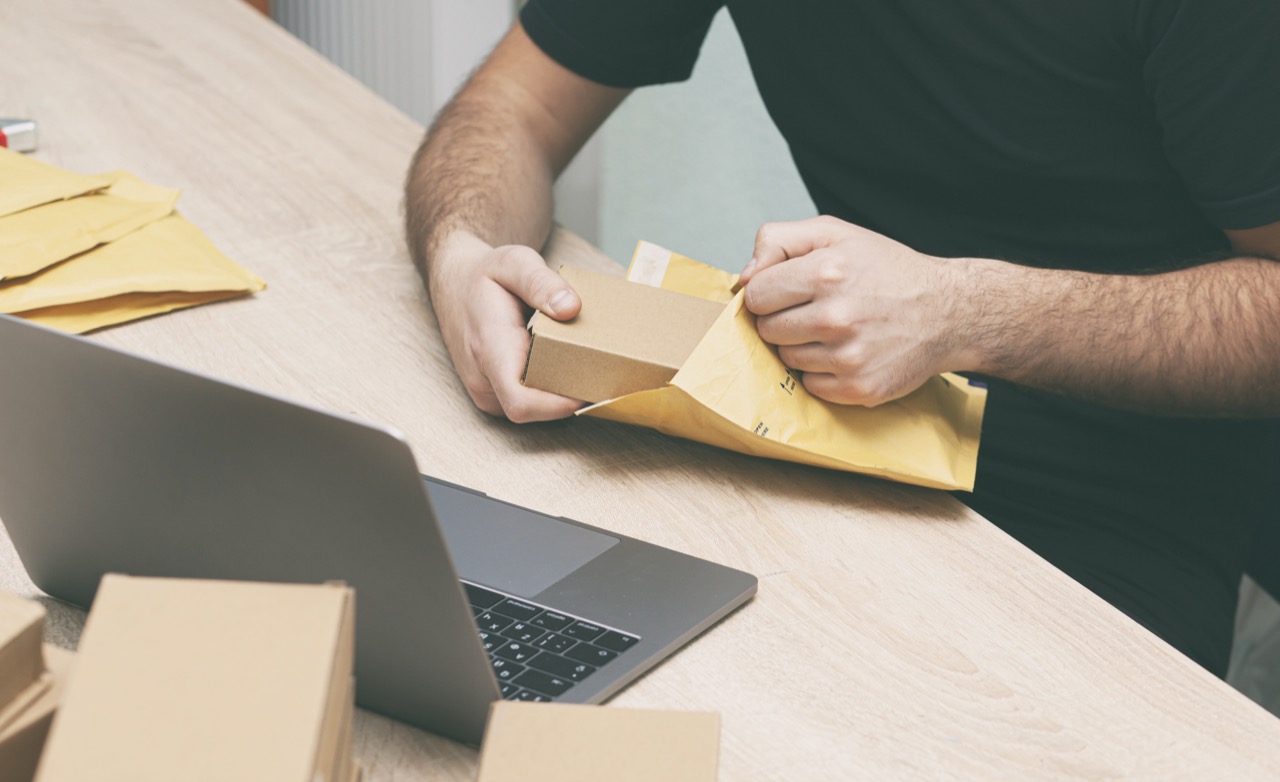 The man is packing the product into the yellow envelope